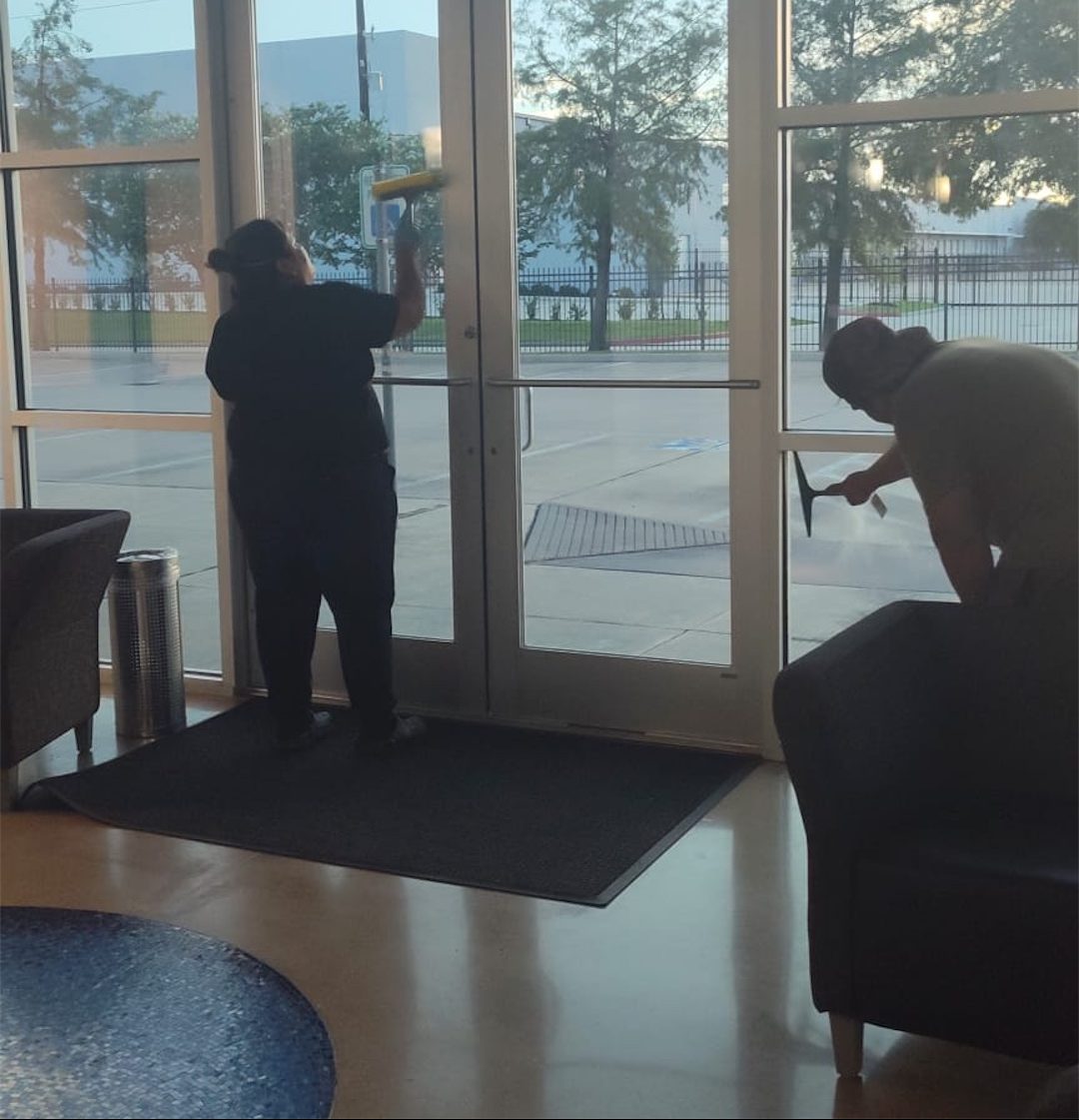 BrightWorks cleaners washing lobby glass doors at a commercial facility in Austin